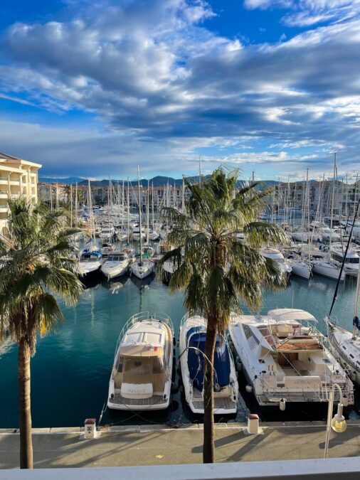 a marina filled with lots of boats under a cloudy blue sky